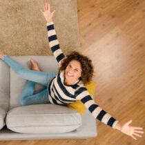 Happy woman at home Top view of a beautiful and woman on the sofa with arms open